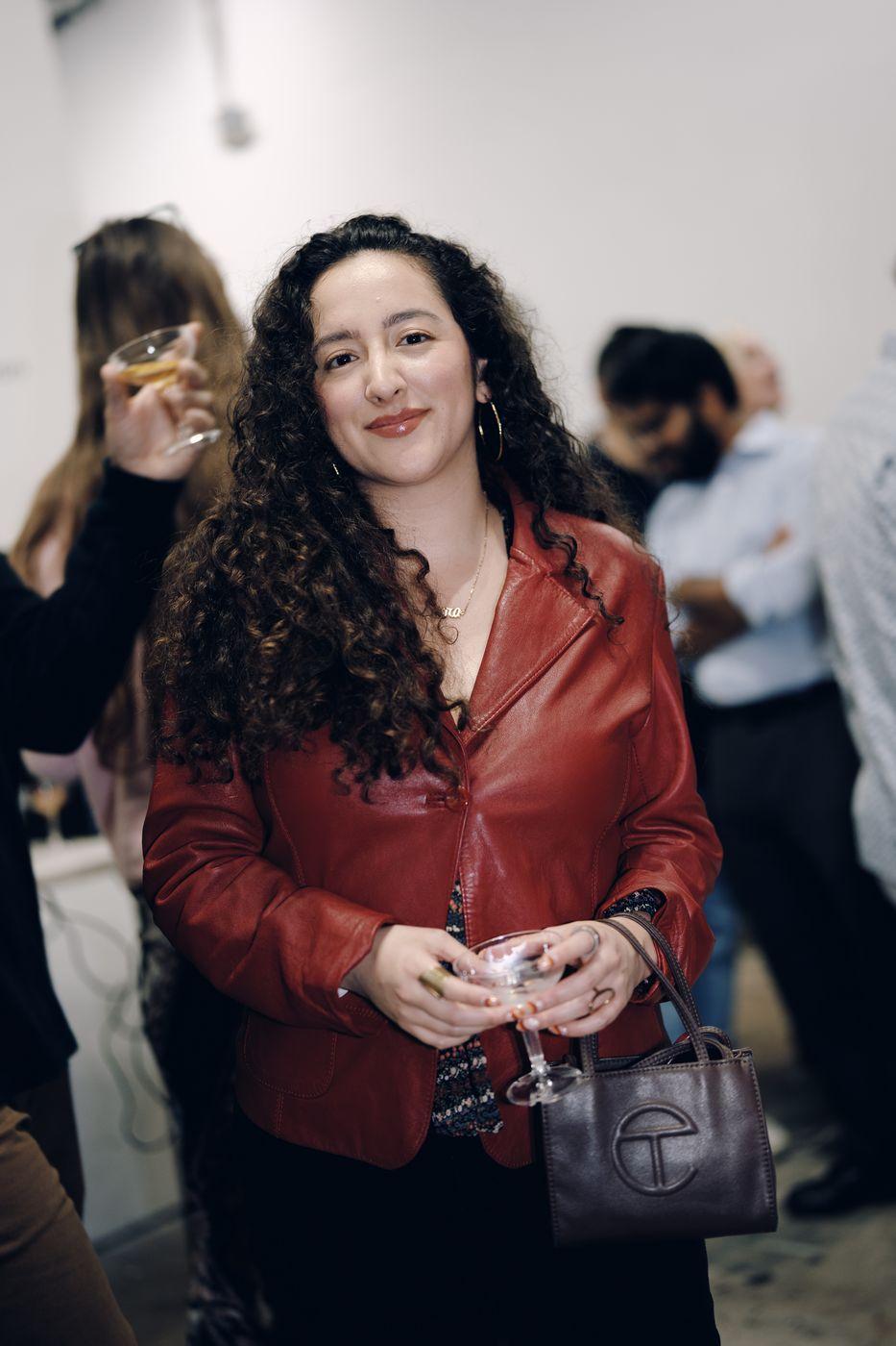 A guest smiling with a drink at a gallery event