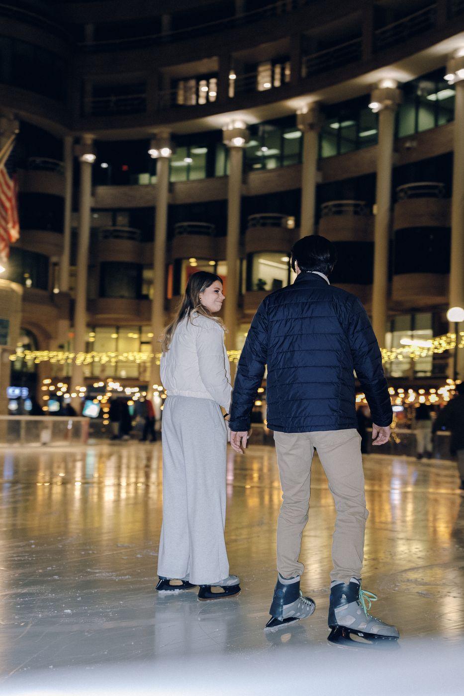 A couple ice skating under string lights